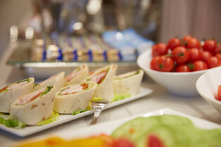Ein Teller mit aufgeschnittenen Wrap‑Röllchen, daneben eine Schale Cherrytomaten und weitere Buffetplatten im Hotel Prinzregent.