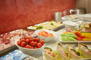 Ein Buffet mit Schalen voller Cherrytomaten, Tomatenscheiben, Wraps sowie Platten mit Aufschnitt, Käse und Gemüse im Hotel Prinzregent.